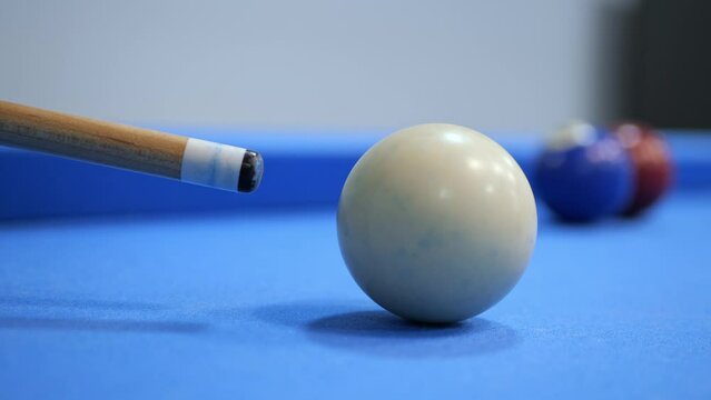 A man's hand strikes the white ball in an American billiard. Close-up of slow motion
