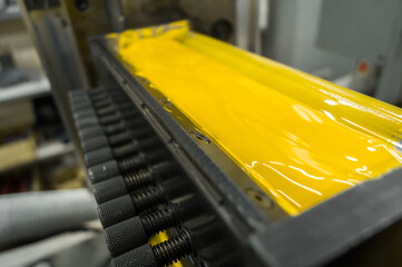 Yellow ink in the paint system compartment of a modern flexographic printing press in a print shop....