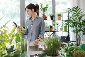 Woman taking care of her plants and using her smartphone