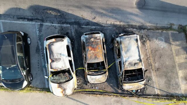 Overhead aerial view of burned cars in a city parking