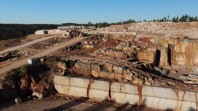 Excavadora trabajando en una mina de m&aacute;rmol transportando un bloque