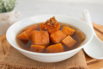 Sweet potato with ginger soup and brown sugar in a white bowl. Traditional Thai food (Thai Dessert). Close-up, Selective focus.