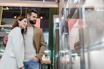happy customers standing near showcase of jewelry store.