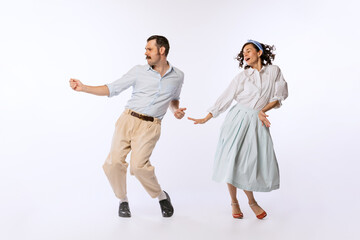 Portrait of young passionate couple, man and woman in retro outfit, dancing isolated over white studio background