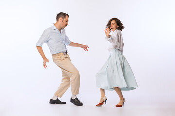 Portrait of young beautiful couple, man and woman, dancing retro dance isolated over white studio...