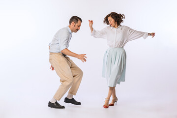 Portrait of young attractive couple, man and woman, dancing isolated over white studio background. Cheerful lifestyle
