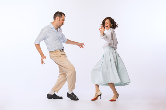 Portrait of young beautiful couple, man and woman, dancing retro dance isolated over white studio background. Romantic date