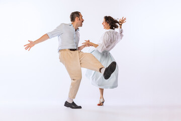 Portrait of young stylish couple, man and woman, dancing isolated over white studio background....