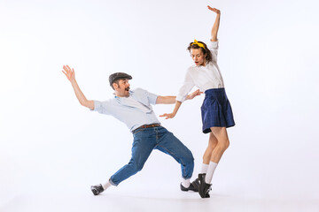 Portrait of young couple, man and woman, dancing isolated over white studio background. Retro style lovers
