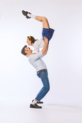 Portrait of young beautiful couple, man and woman, dancing retro dance isolated over white studio background. Flexibility