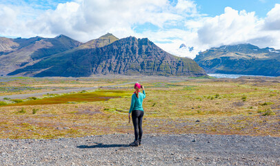 Pretty girl wearing green t-shirt is making selfie with smartphone on background of mountains - Iceland