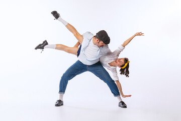 Portrait of young beautiful couple, man and woman, dancing isolated over white studio background. Extravagant dance moves