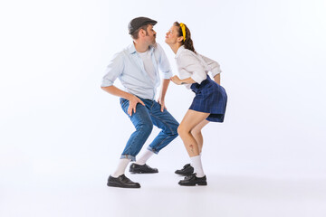 Portrait of young beautiful couple, man and woman, dancing retro dance isolated over white studio background. Funny faces