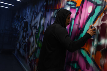 Side view of african american vandal painting graffiti on wall - obrazy, fototapety, plakaty