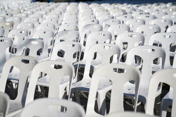 Fototapeta premium Many white plastic chairs were set up in a square area with the row and column for outdoor concerts or open air events.