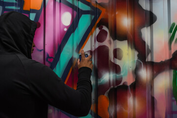 African american hooligan drawing graffiti on wall on street - obrazy, fototapety, plakaty