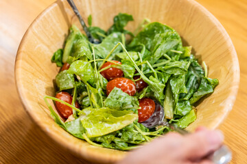 A closeup shot of a delicious vegetable salad on wooden bowl cooking in kitchen at home.