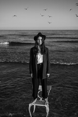 artistic dreamer portrait of girl in a formal elegant stylish suit, shirt and hat standing on a...