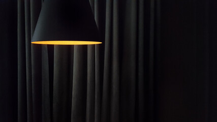 Close-up on a modern lamp against the background of the folds of curtains in dark colors with copy...