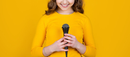 cropped view of teen child with microphone on yellow background