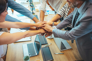 Top view of creative professionals putting their hands together as a symbol of teamwork,...