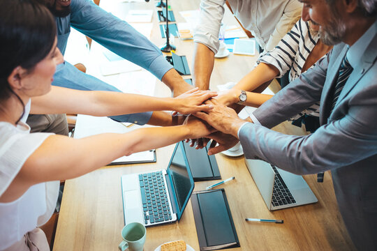 Group of business workers standing with hands together at the office. Stack of hands. Unity and teamwork concept. Close up view of young business people putting their hands together.