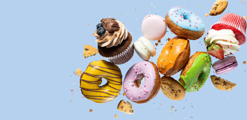Colorful decorated donuts, chocolate cookies, cupcakes, confectionery and macaroons falling in...