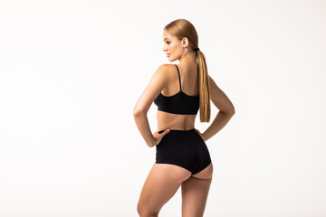 Fototapeta premium Well-kept skin, perfect buttocks. Back view of beautiful body of young caucasian woman in black lingerie isolated on gray studio background. Natural beauty, treatment, fitness and diet concept.