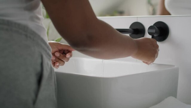  Close up of African-American person washing hands in the sink and using white towel. Shot with RED helium camera in 8K.  