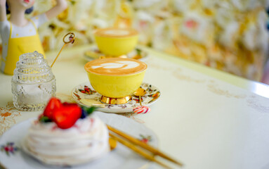 An elegant yellow cup with fragrant coffee, a transparent sugar bowl and meringue with berries. Cafe background. Sweets confectionery. Natural coffee concept.