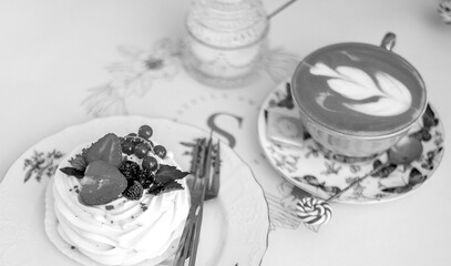 Black and white banner with an elegant cup of natural coffee and a dessert with berries. Confectionery. Sweets. Holiday day concept.