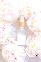 White Cream bottle and peony flowers background. Cosmetic skincare product blank frosted glass...