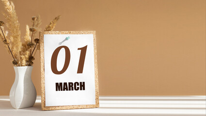 march 1. 1th day of month, calendar date.White vase with dead wood next to cork board with numbers. White-beige background with striped shadow. Concept of day of year, time planner, spring month
