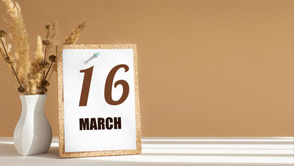 march 16. 16th day of month, calendar date.White vase with dead wood next to cork board with numbers. White-beige background with striped shadow. Concept of day of year, time planner, spring month