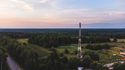 Fototapeta premium cell tower in the evening against the background of the forest and sky