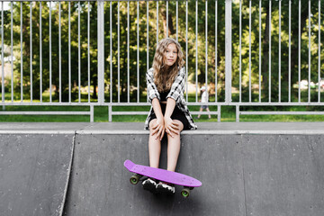 Active child with penny board sitting on skate sport ramp. Extreme sport lifestyle. Creative advertising for sports children store.