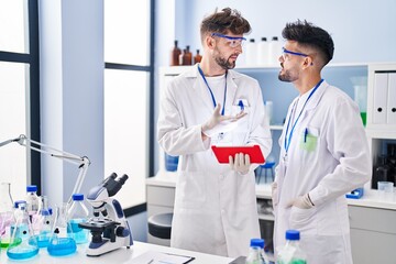 Young couple wearing scientist uniform using touchpad at laboratory