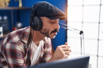 Young hispanic man musician listening to music at music studio
