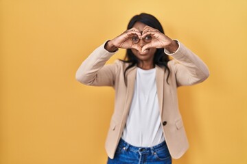 African young woman wearing glasses smiling in love doing heart symbol shape with hands. romantic concept.