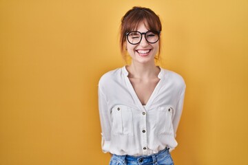 Young beautiful woman wearing casual shirt over yellow background winking looking at the camera...