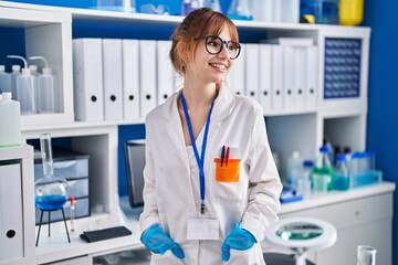 Young woman scientist smiling confident standing at laboratory