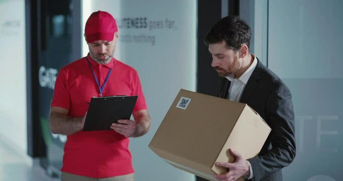 Bearded office manager man receiving crashed fragile parcel box arguing with careless adult courier in office department. Conflict, emotions.