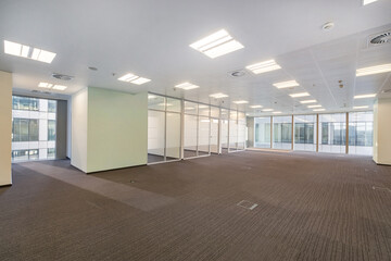 Open bright office space with brown carpet and panoramic windows. Unfurnished.