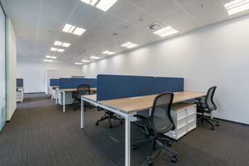 Bright office open space with gray flooring and work areas with white furniture.