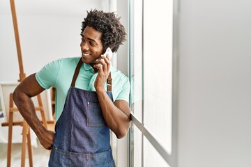 Young african american artist man talking on the smartphone standing at art studio.