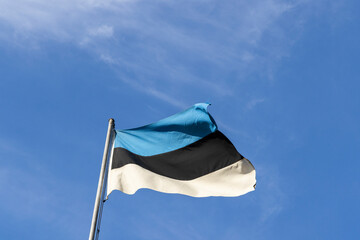Estonian national flag flying on the pole with the summer sky background