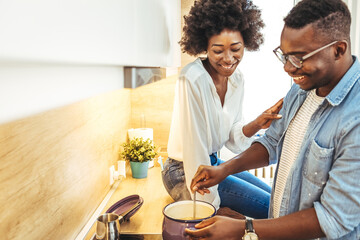 Cooked with love. Cute laughing blonde frying something in skillet. Couple preparing food in kitchen. Couple preparing food in the kitchen of their cozy loft apartment