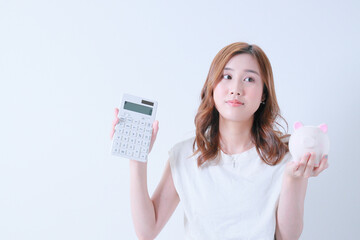計算機と貯金箱を持ったＴシャツ姿の女性