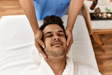 Man smiling happy reciving head massage at beauty center.