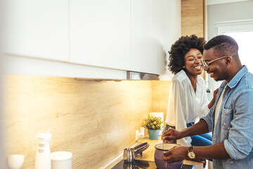 Young man cooking with girlfriend and adding spice to the sauce. Multiethnic couple preparing lunch...